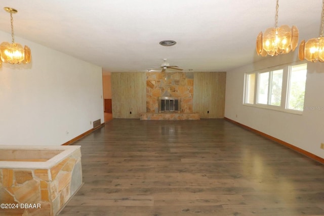 unfurnished living room featuring dark hardwood / wood-style floors, a fireplace, and ceiling fan with notable chandelier