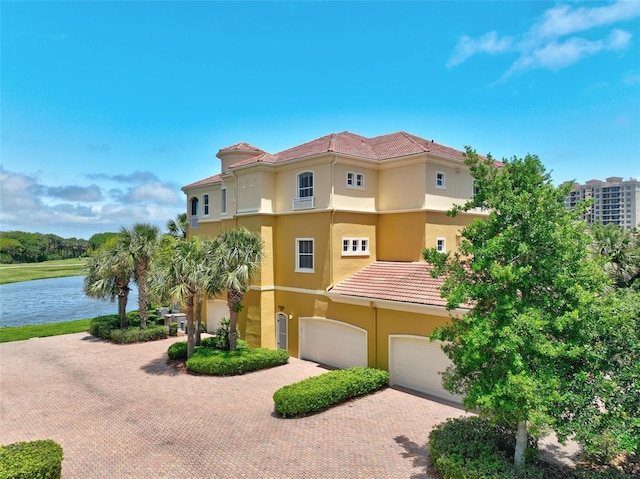 mediterranean / spanish-style house with a garage and a water view