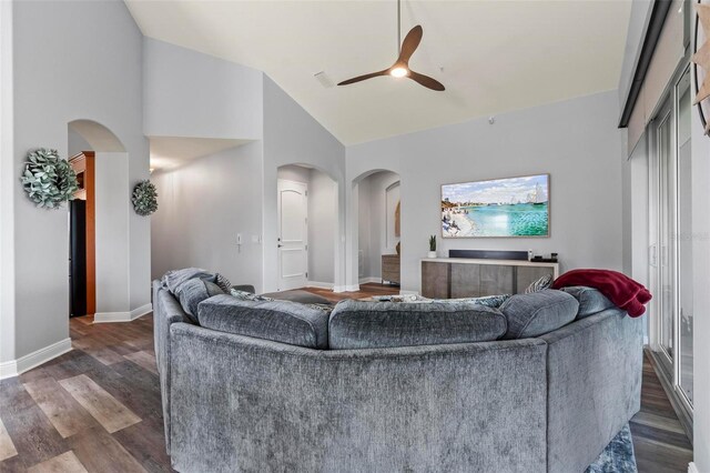 living room with high vaulted ceiling, ceiling fan, and dark wood-type flooring