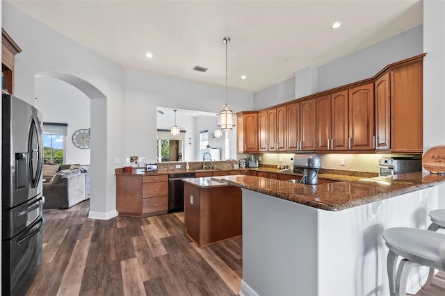 kitchen featuring stainless steel fridge with ice dispenser, tasteful backsplash, kitchen peninsula, and pendant lighting