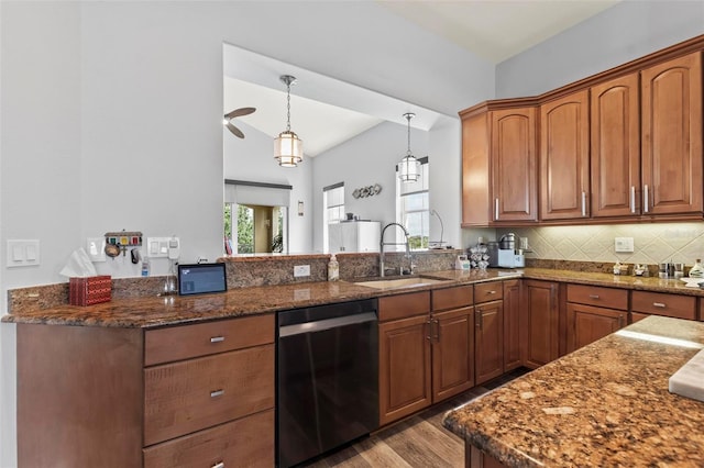 kitchen with decorative light fixtures, dishwashing machine, light hardwood / wood-style floors, sink, and dark stone counters