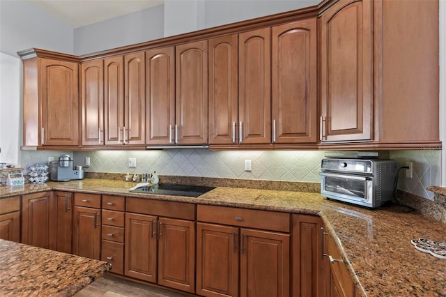 kitchen featuring light hardwood / wood-style floors, black electric stovetop, light stone counters, and tasteful backsplash