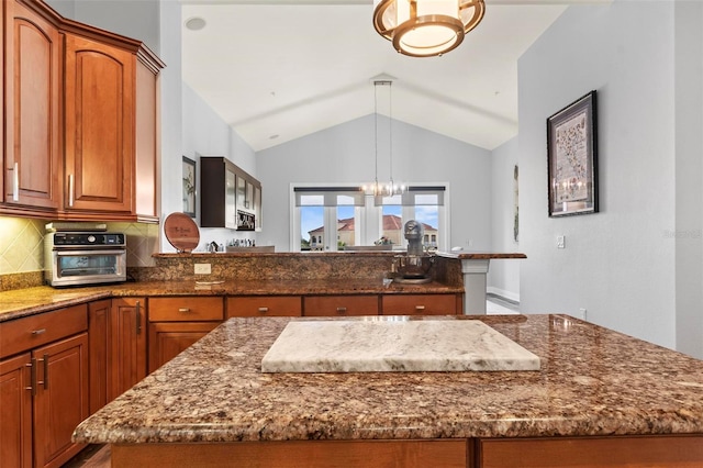kitchen featuring dark stone counters, a kitchen island, decorative backsplash, and pendant lighting