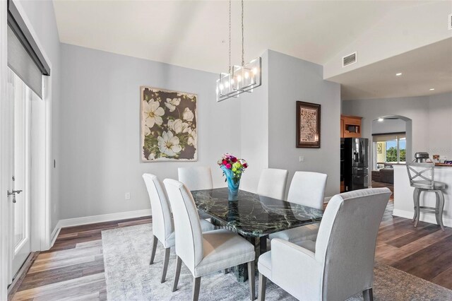 dining room with a notable chandelier, vaulted ceiling, and dark hardwood / wood-style floors