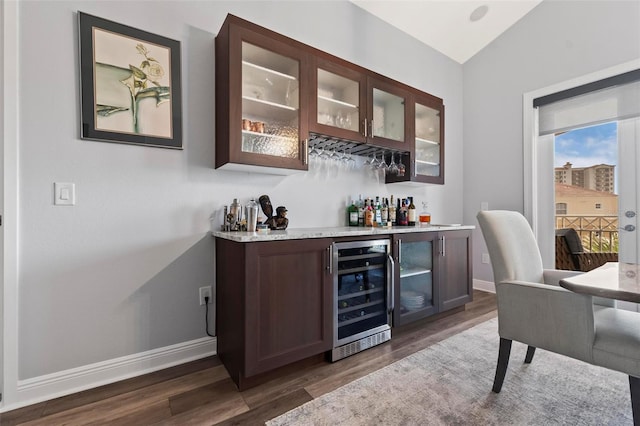 bar featuring dark wood-type flooring, lofted ceiling, wine cooler, and dark brown cabinetry
