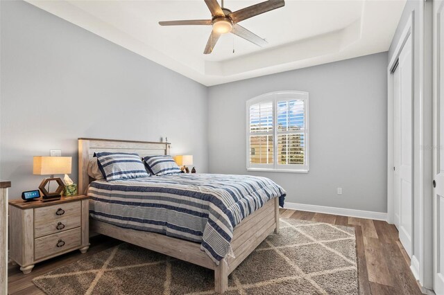 bedroom featuring ceiling fan, a raised ceiling, a closet, and hardwood / wood-style flooring