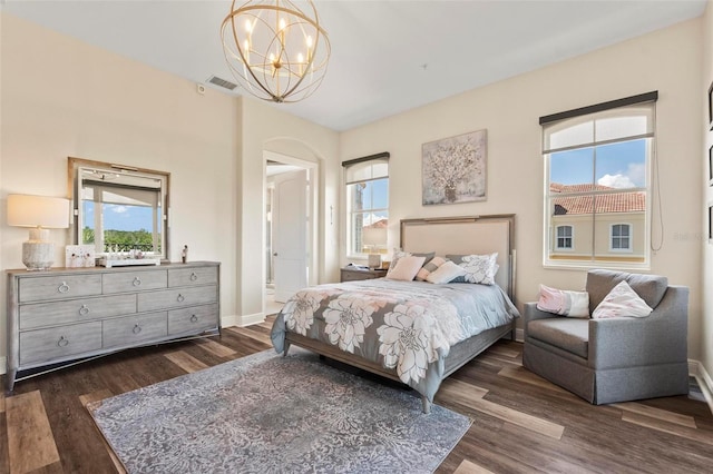 bedroom featuring dark hardwood / wood-style flooring, multiple windows, and a notable chandelier