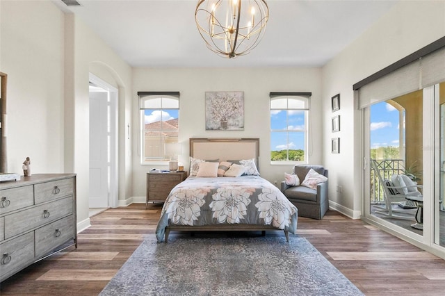 bedroom with hardwood / wood-style flooring, access to outside, and an inviting chandelier