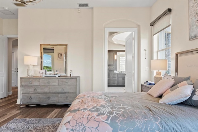 bedroom with dark hardwood / wood-style flooring and connected bathroom