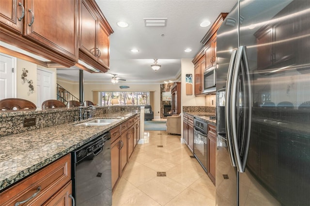 kitchen featuring dark stone counters, sink, ceiling fan, light tile patterned floors, and appliances with stainless steel finishes