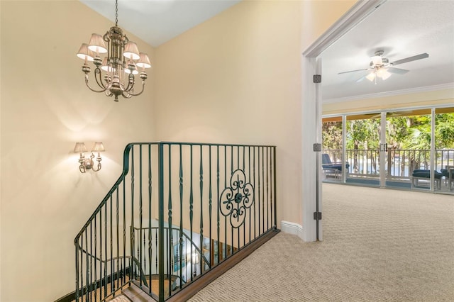 stairs with vaulted ceiling, carpet floors, ceiling fan with notable chandelier, and ornamental molding