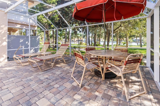 view of patio / terrace featuring a lanai and a water view