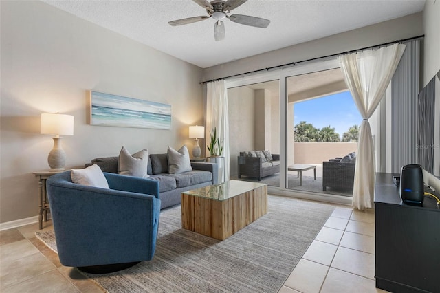 living room with ceiling fan, light tile patterned floors, and a textured ceiling