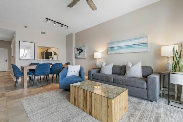 living room with ceiling fan, rail lighting, and a textured ceiling