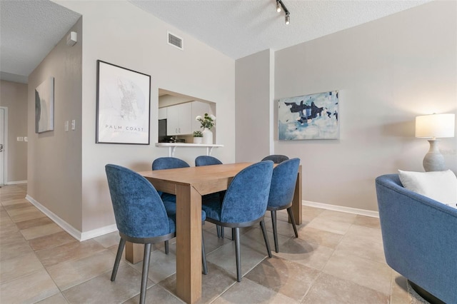 dining space featuring a textured ceiling and rail lighting