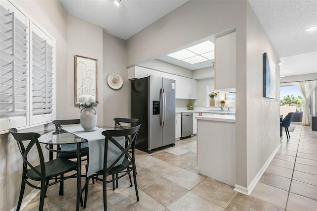 kitchen with appliances with stainless steel finishes, a textured ceiling, white cabinetry, and sink