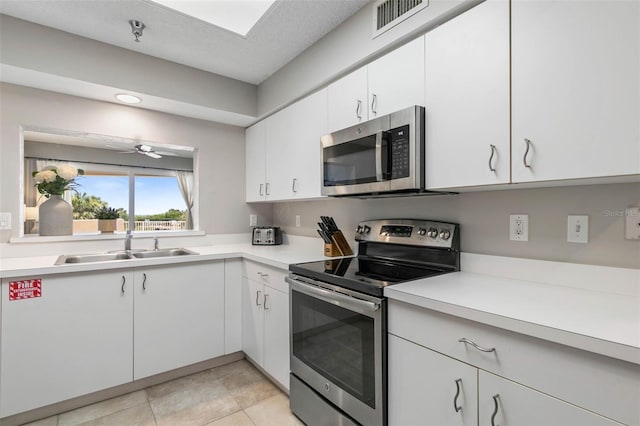 kitchen featuring ceiling fan, sink, a textured ceiling, white cabinets, and appliances with stainless steel finishes