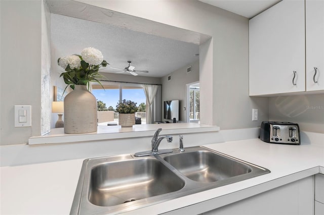 kitchen with white cabinetry, sink, ceiling fan, and a textured ceiling