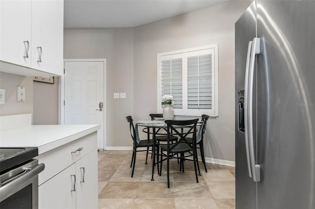 kitchen with white cabinets, stainless steel refrigerator with ice dispenser, and light tile patterned floors