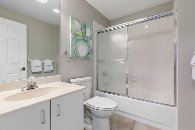 full bathroom with vanity, tile patterned floors, combined bath / shower with glass door, toilet, and a textured ceiling