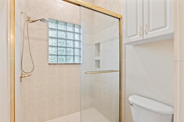 bathroom featuring a shower with door and toilet