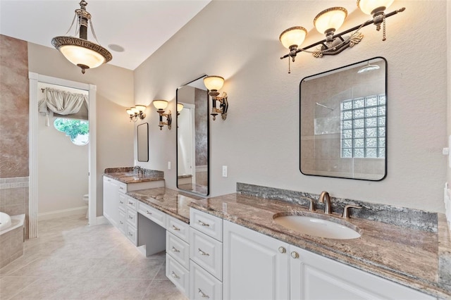 bathroom with tiled tub, tile patterned flooring, vanity, and toilet