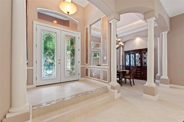 tiled entrance foyer featuring a chandelier, ornamental molding, and french doors