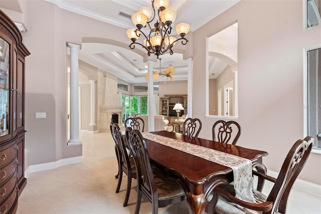 dining room with a high end fireplace, a tray ceiling, ornate columns, and a notable chandelier