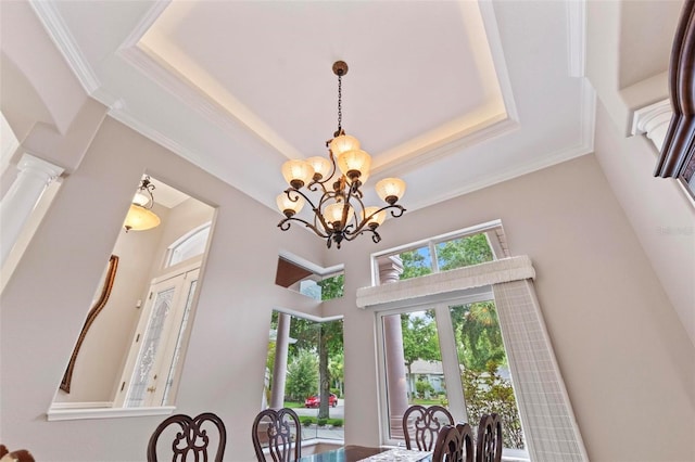 dining area with a raised ceiling, a towering ceiling, ornamental molding, and a notable chandelier