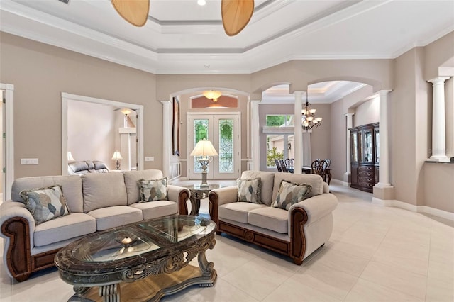 tiled living room with decorative columns, crown molding, and ceiling fan with notable chandelier