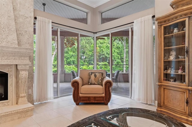 living area with a high end fireplace, crown molding, and light tile patterned floors