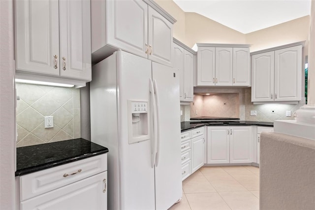 kitchen featuring lofted ceiling, backsplash, white fridge with ice dispenser, light tile patterned floors, and white cabinetry