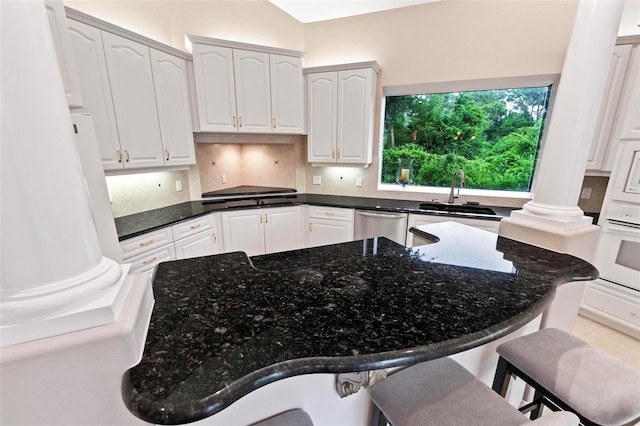 kitchen featuring dishwasher, a breakfast bar, white oven, sink, and white cabinetry