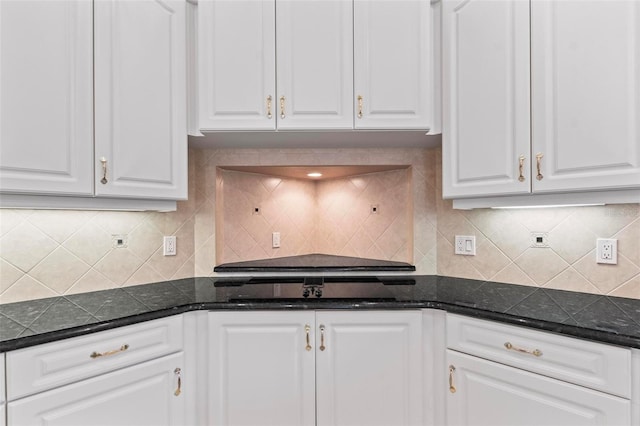 kitchen with tasteful backsplash, white cabinetry, and dark stone countertops