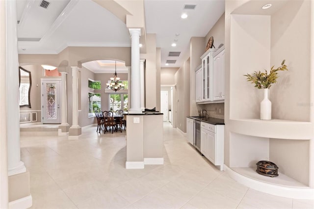 kitchen featuring white cabinets, sink, a chandelier, ornamental molding, and decorative columns