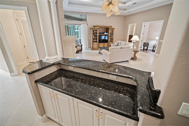 interior space with ceiling fan, tile patterned flooring, decorative columns, crown molding, and a tray ceiling