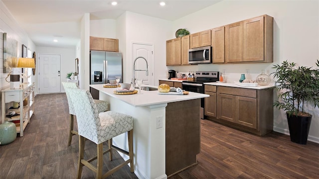 kitchen featuring a kitchen bar, a center island with sink, sink, dark hardwood / wood-style flooring, and stainless steel appliances