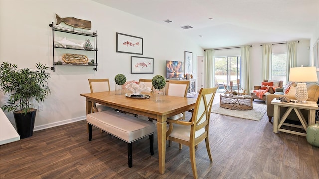 dining area with dark wood-type flooring and vaulted ceiling