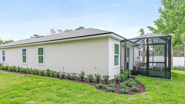 view of home's exterior with a lawn and glass enclosure