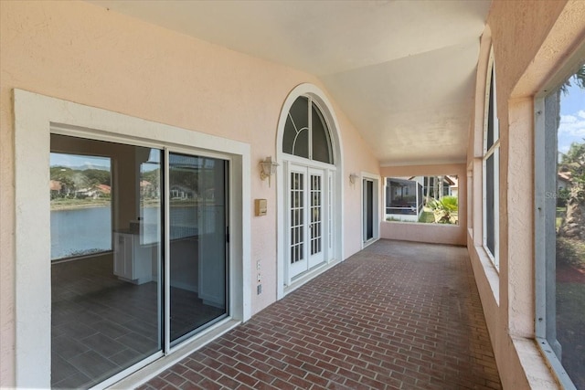 unfurnished sunroom featuring french doors, a water view, and lofted ceiling