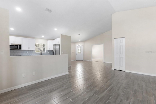 unfurnished living room with an inviting chandelier and lofted ceiling