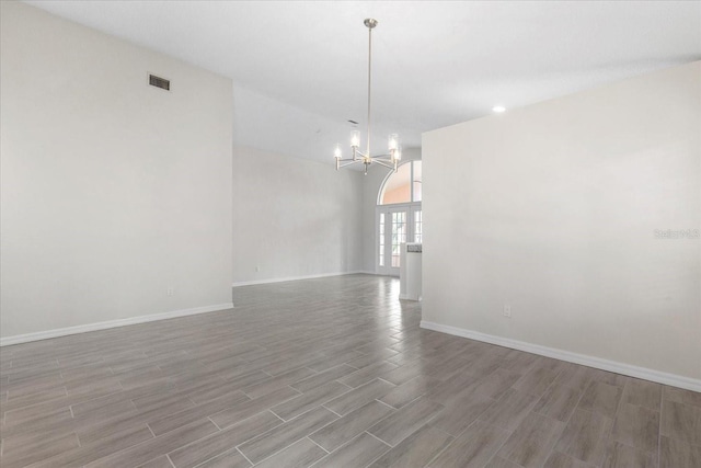 empty room with a chandelier and light wood-type flooring