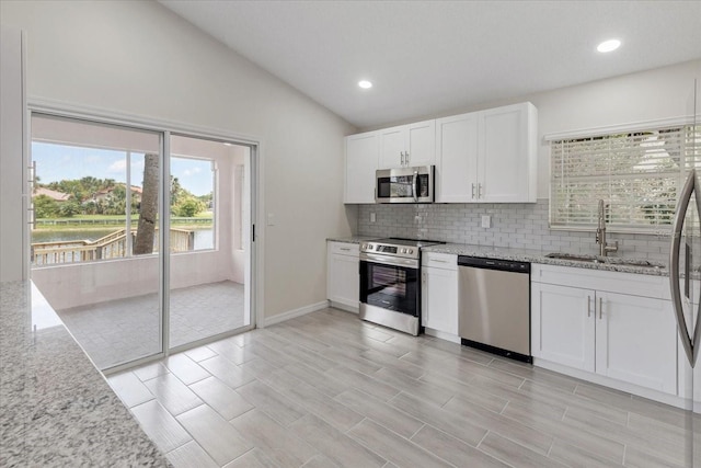 kitchen with white cabinetry, sink, stainless steel appliances, and light stone countertops