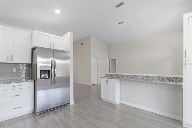 kitchen featuring tasteful backsplash, white cabinetry, light stone counters, and stainless steel fridge with ice dispenser