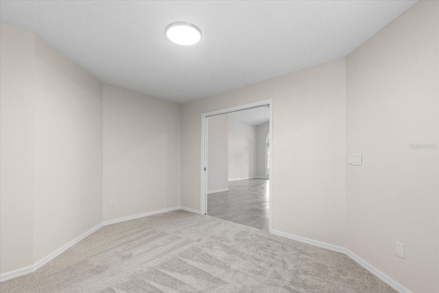 carpeted empty room featuring a textured ceiling