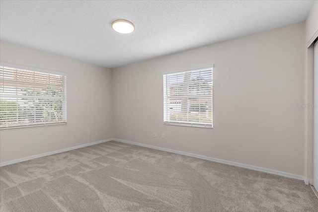 carpeted empty room featuring a textured ceiling