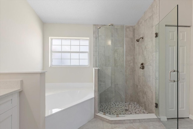 bathroom with tile patterned flooring, vanity, shower with separate bathtub, and a textured ceiling