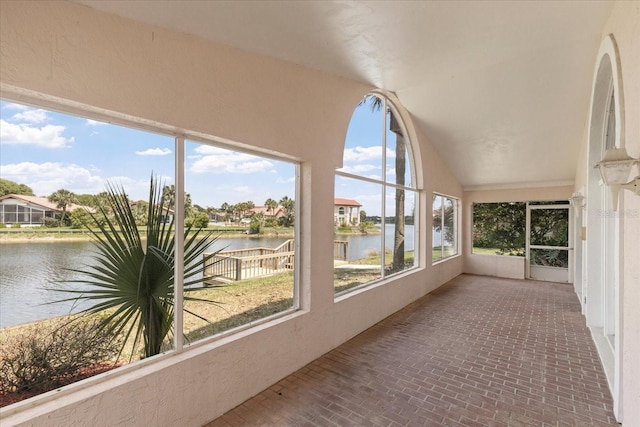 unfurnished sunroom featuring vaulted ceiling and a water view