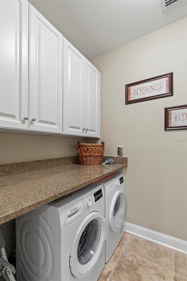 laundry area featuring cabinets, a textured ceiling, and washing machine and dryer