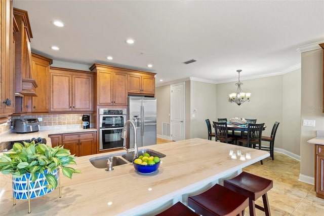 kitchen featuring stainless steel appliances, an inviting chandelier, tasteful backsplash, pendant lighting, and ornamental molding